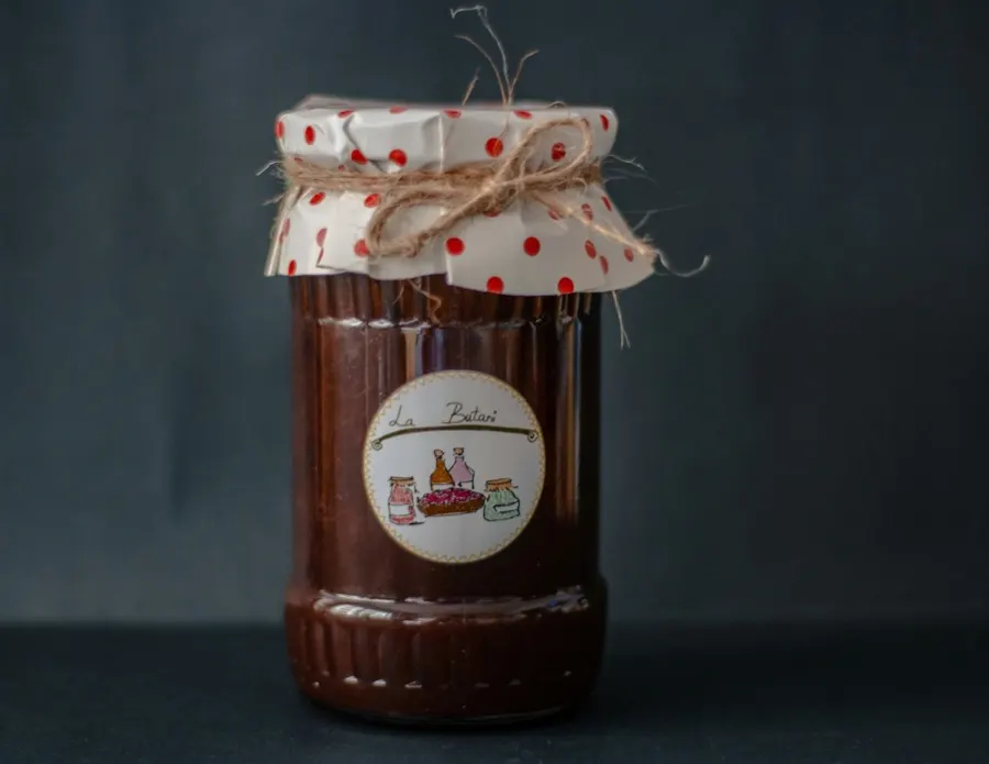 A jar of apple and ale chutney topped with a spotted cloth cap