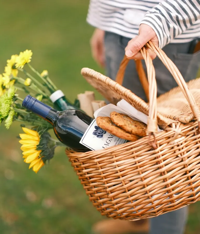 A wicker hamper carried through the orchard, packed with bread and wine