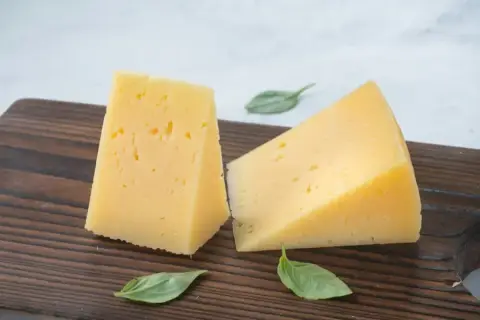 Wedges of golden oak-smoked cheese on a dark board